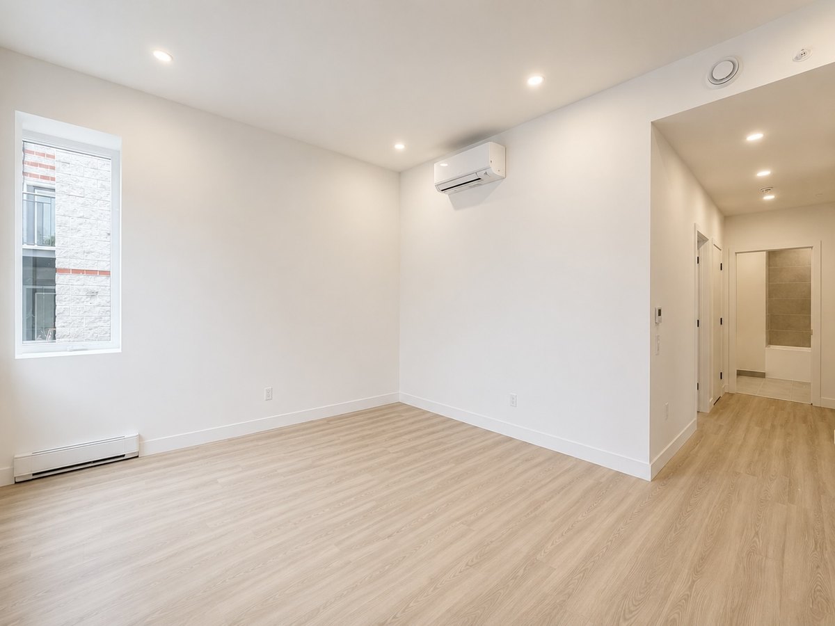 Rosemont : pièce de vie lumineuse avec plancher clair et passage vers la salle de bain.